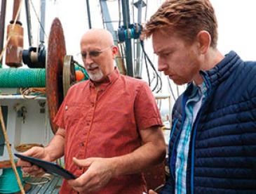 Two people using technology for fisheries and climate-resilient oceans